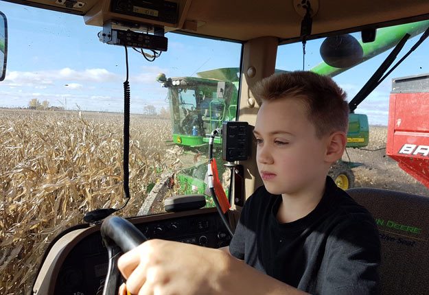 Les enfants participent aux travaux à la ferme de leurs parents depuis des siècles. Antoine Jodoin, huit ans, s’initie graduellement à la conduite du tracteur, sous la supervision d’un adulte. Crédit Photo : Gracieuseté de François Jodoin