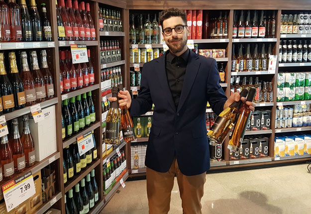 Jason Gaouette pose devant sa section des boissons alcoolisées qui, grâce à la nouvelle loi, pourra offrir une plus grande diversité de produits québécois. Cette loi devrait par ailleurs faire croître la filière des vins, cidres, hydromels et autres boissons confectionnées au Québec. Crédit Photo : Martin Ménard/TCN