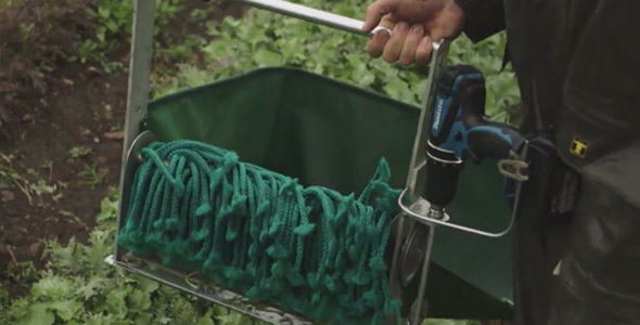 La récolteuse à mesclun fonctionne à l’aide d’une perceuse qui fait tourner les cordes bungee pour envoyer la salade dans le sac.