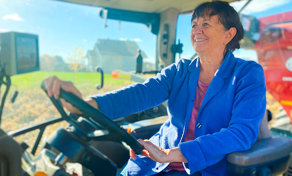 Jeanne Chalifoux-Leblanc suit la moissonneuse-batteuse avec son tracteur pour transporter cette récolte record de maïs.