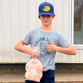 Scott Désilets, 12 ans, tient un de ses poulets qu’il a lui-même élevé et vendu au cours de l’été. Photo : Gracieuseté de Mélanie Vincent