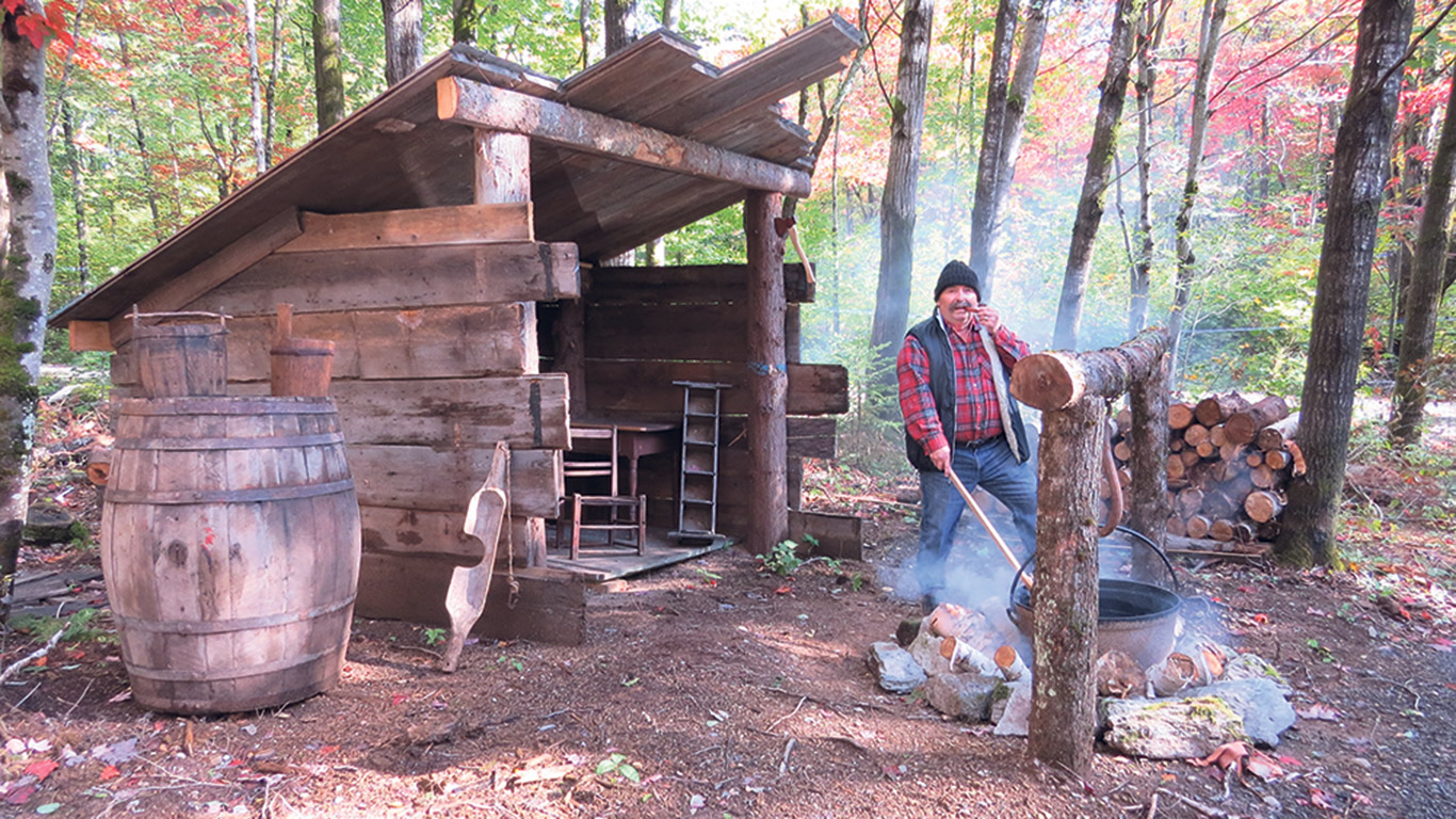 Réjean Bilodeau devant un bâtiment qui reproduit une ancienne cabane à sucre. Photo : Gracieuseté de Réjean Bilodeau