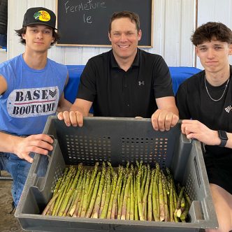 Julien Pagé, entouré de ses fils Justin et Antoine, passe plus de 15 heures par jour à récolter des asperges. Crédit : Gracieuseté de Julien Pagé