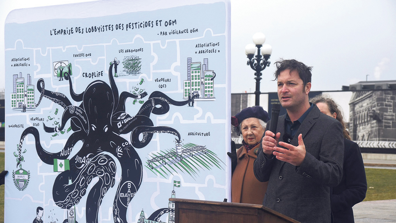 Thibault Rehn s’est rendu à Ottawa, le 28 novembre, pour diffuser une carte répertoriant les lobbyistes du milieu agricole qui militent en faveur des pesticides et des OGM. Photo : Vigilance OGM